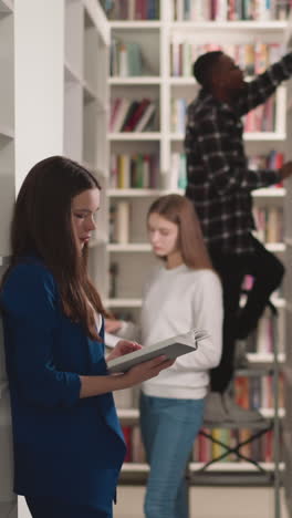 students work with literature in public library. young women read books and black man stands on step ladder in bookstore. college education