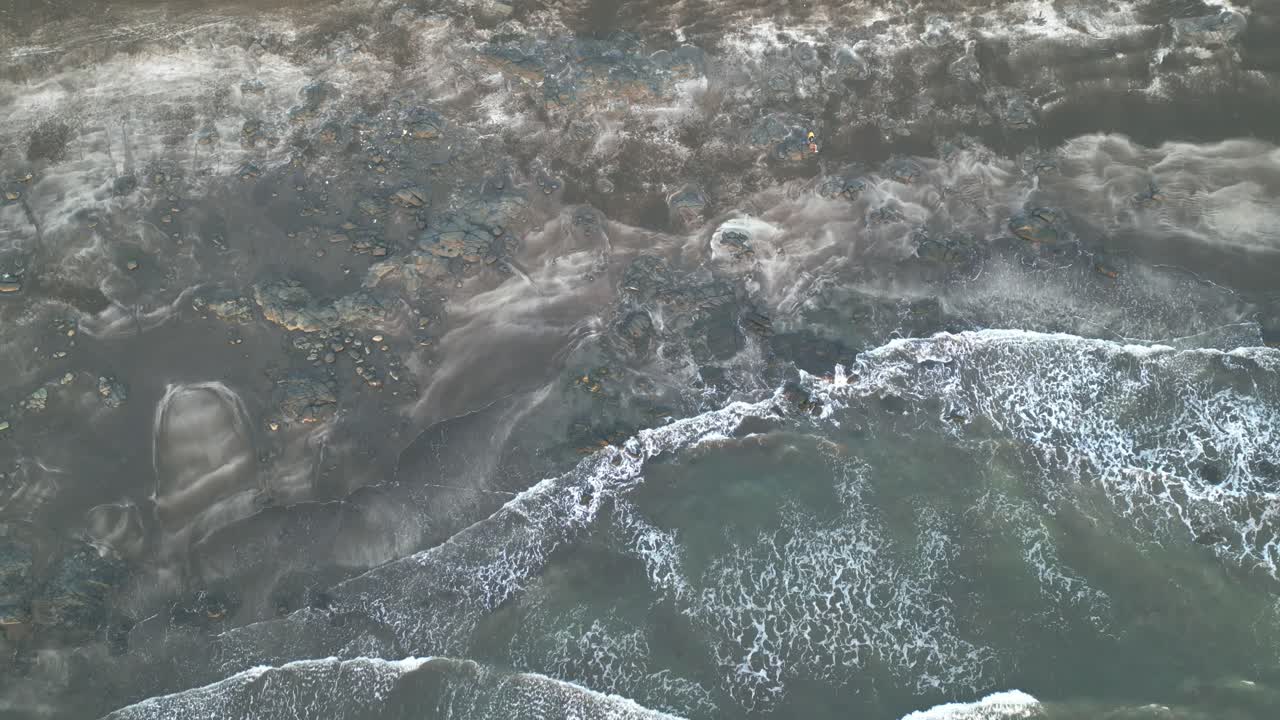 A stunning top drone view of waves gracefully rolling onto the peaceful shores of Harihareshwar Beach in Maharashtra, showcasing nature’s serene beauty in perfect harmony 4K
