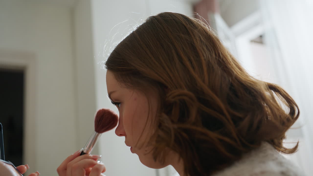 White Woman Giving Final Playful Makeup Flourish, Puff Brush Near Lips And Cheek While Checking Compact Mirror, Bright Natural Light, Relaxed Confident Vibe Before Stepping Out, Soft Hair Bounce