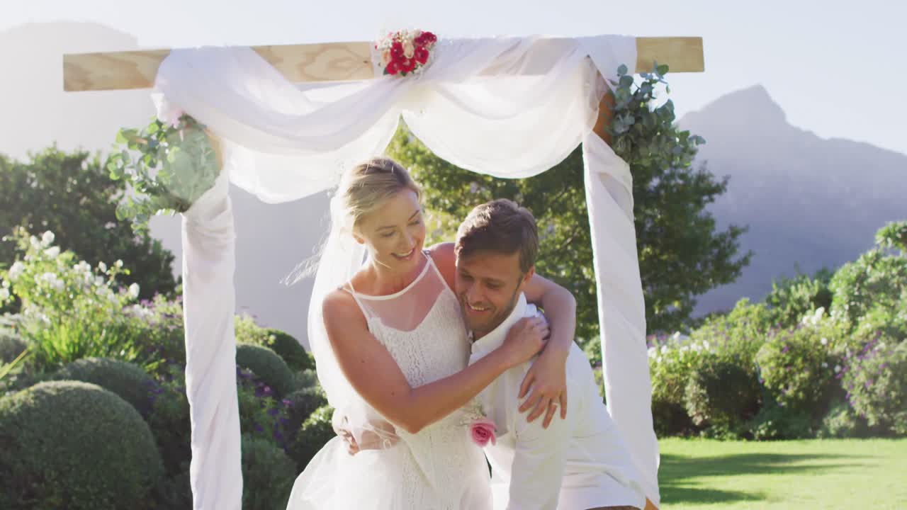 Happy caucasian husband carries newly wed bride and walks down altar outdoors