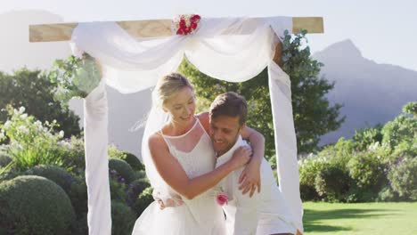 Feliz-Marido-Caucásico-Lleva-A-La-Novia-Recién-Casada-Y-Camina-Por-El-Altar-Al-Aire-Libre