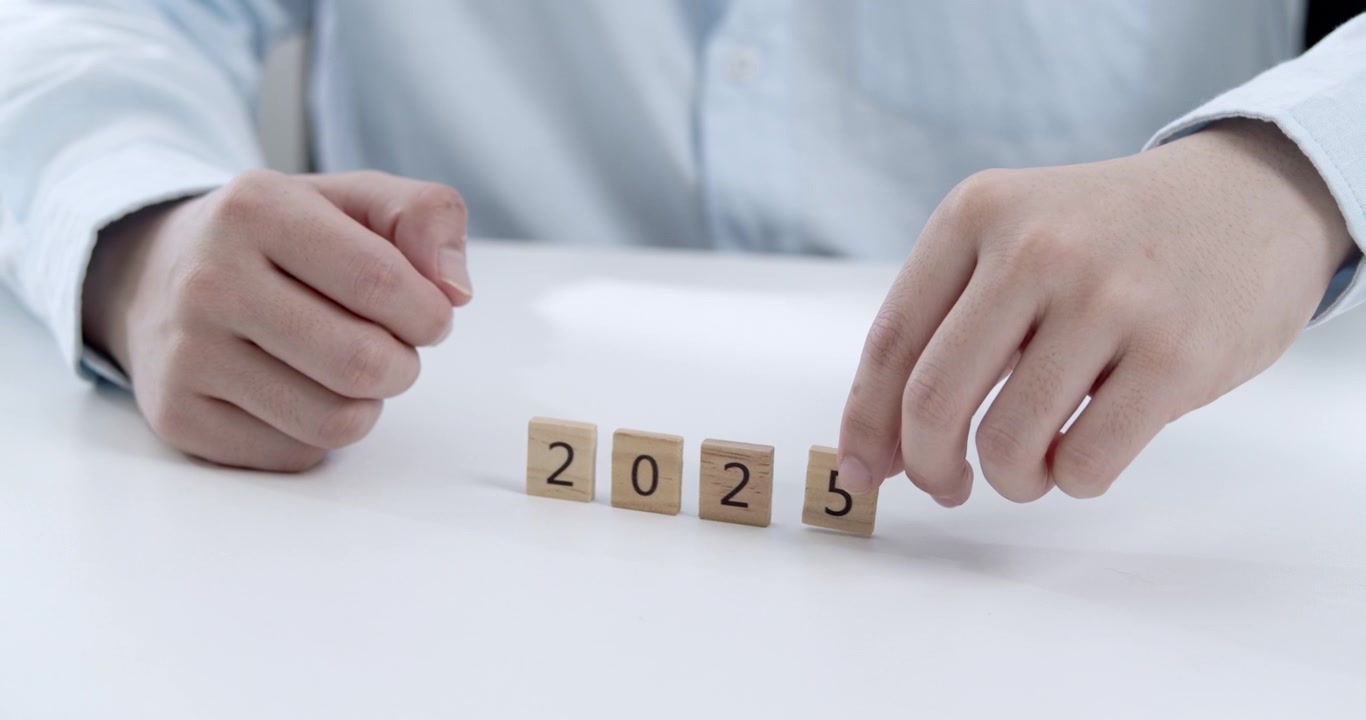 Mãos de empresário substituindo o número 4 pelo 5 para a mudança de 2024 para 2025, ilustrando o planeamento de metas, colaboração empresarial e a entrada numa nova fase de sucesso