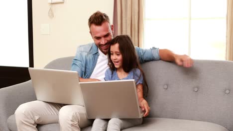padre y hija felices usando portátiles