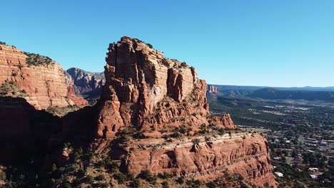 Sandstone-mountains-and-small-town-of-Sedona-bellow,-aerial-orbit-shot