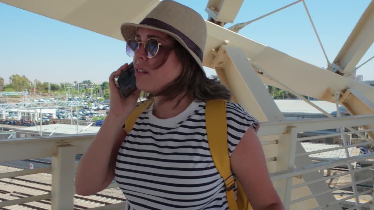 A tourist woman talks on her cell phone while walking on a bridge before boarding a ship.
