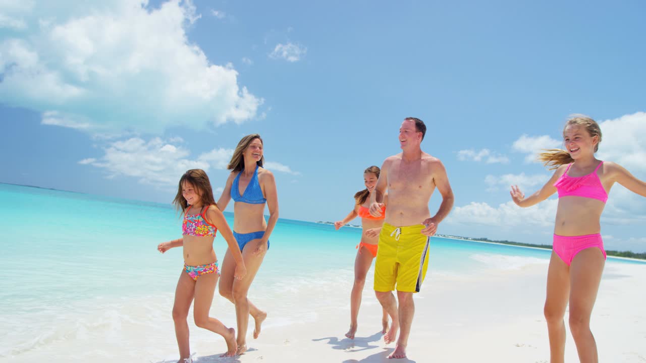 Caucasian family in swimwear playing on beach vacation