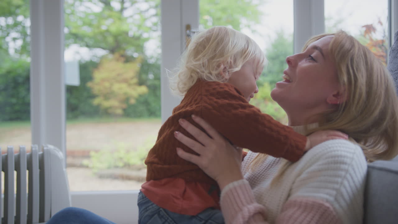 생활 비용 에너지 위기 동안 집에서 게임을하는 라디에이터 플러그를 가진 어머니와 아들이