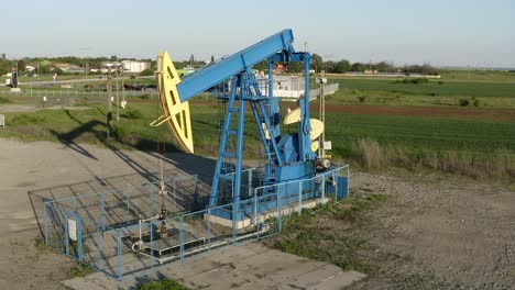 aerial: old oil pump rig in countryside, pulley extracting oil from ground