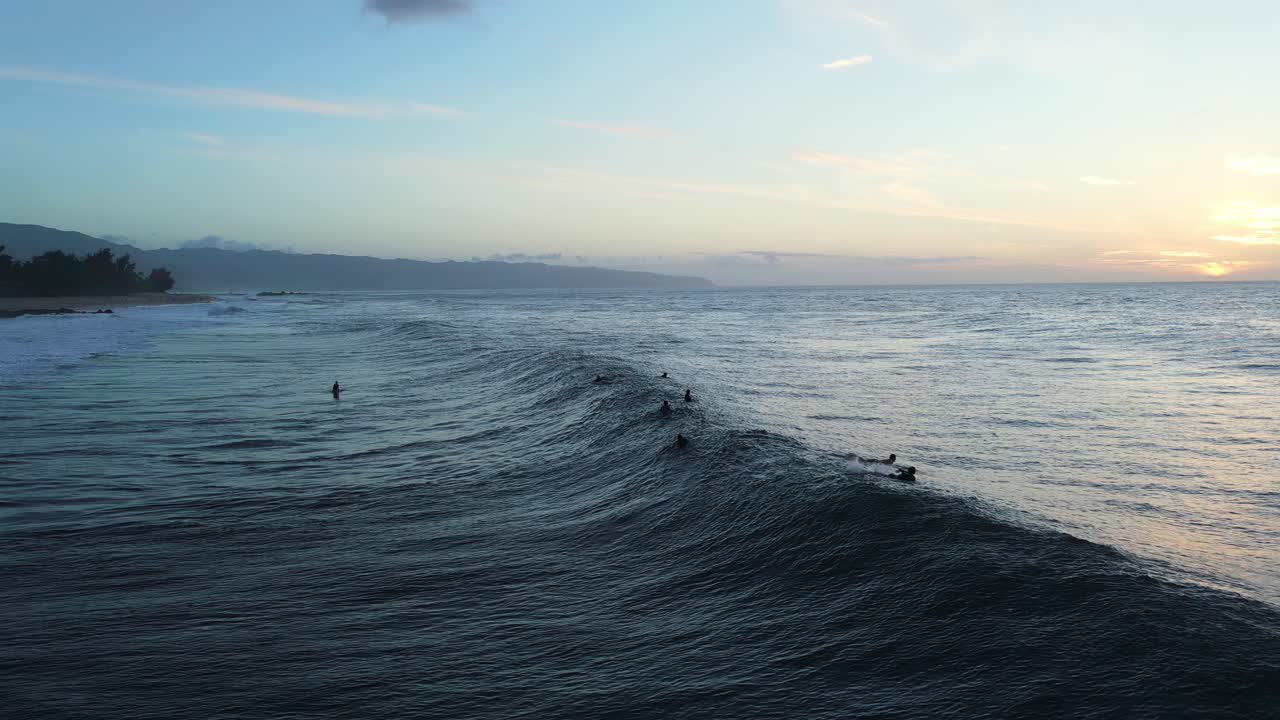 surfistas al atardecer con olas rompiendo cerca de la playa de pupukea en la isla de oahu