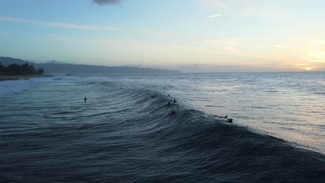 Surfers-at-sunset-with-wave-breaking-near-Pupukea-beach-on-Oahu-island