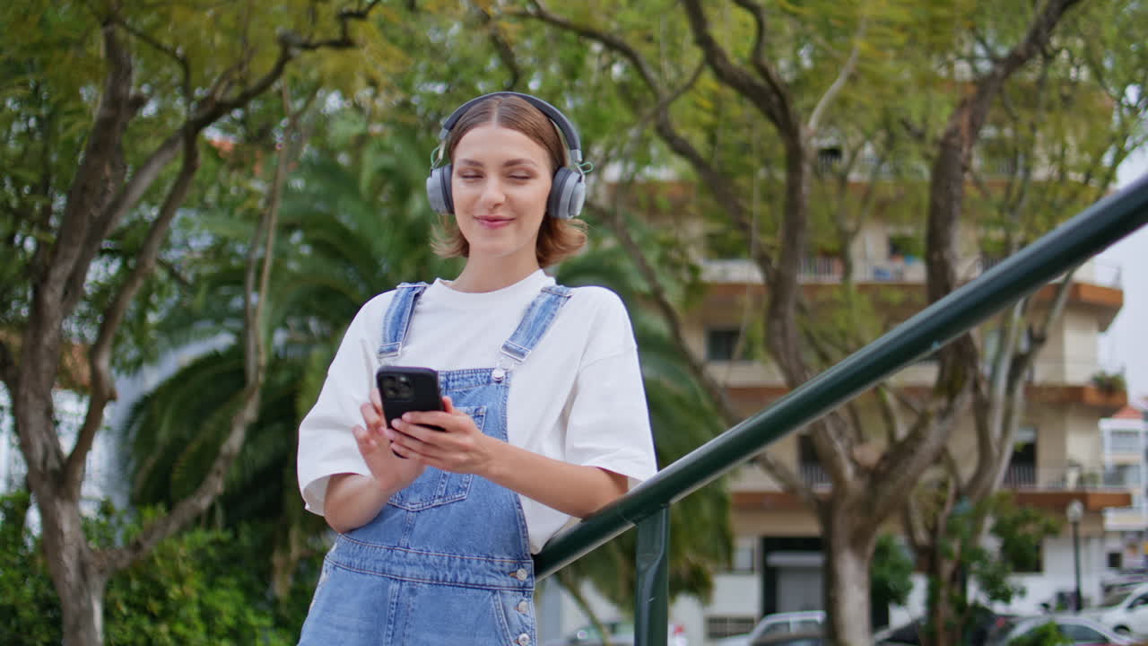 Carefree teenager enjoy music in earphones turning on phone app at park closeup