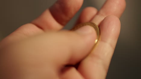 sosteniendo una pieza de una moneda conmemorativa de oro y volviéndola en la mano de la persona
