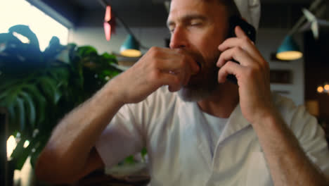 Male-chef-having-breakfast-while-talking-on-mobile-phone-at-counter-4k