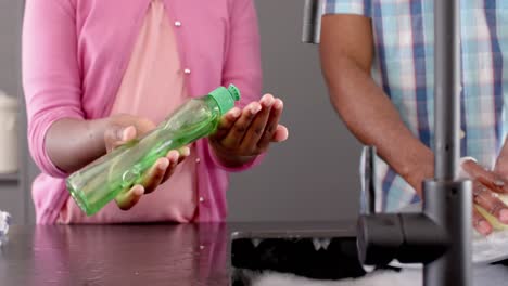 Midsection-of-african-american-daughter-and-father-washing-dishes-in-kitchen,-slow-motion