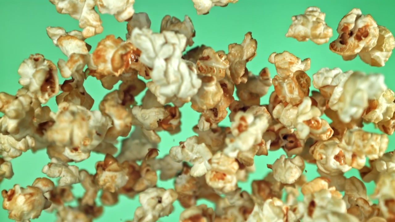 Deliziosi popcorn che volano e cadono al rallentatore su schermo verde