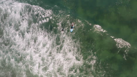 surfer paddles out with instructor into breaking waves