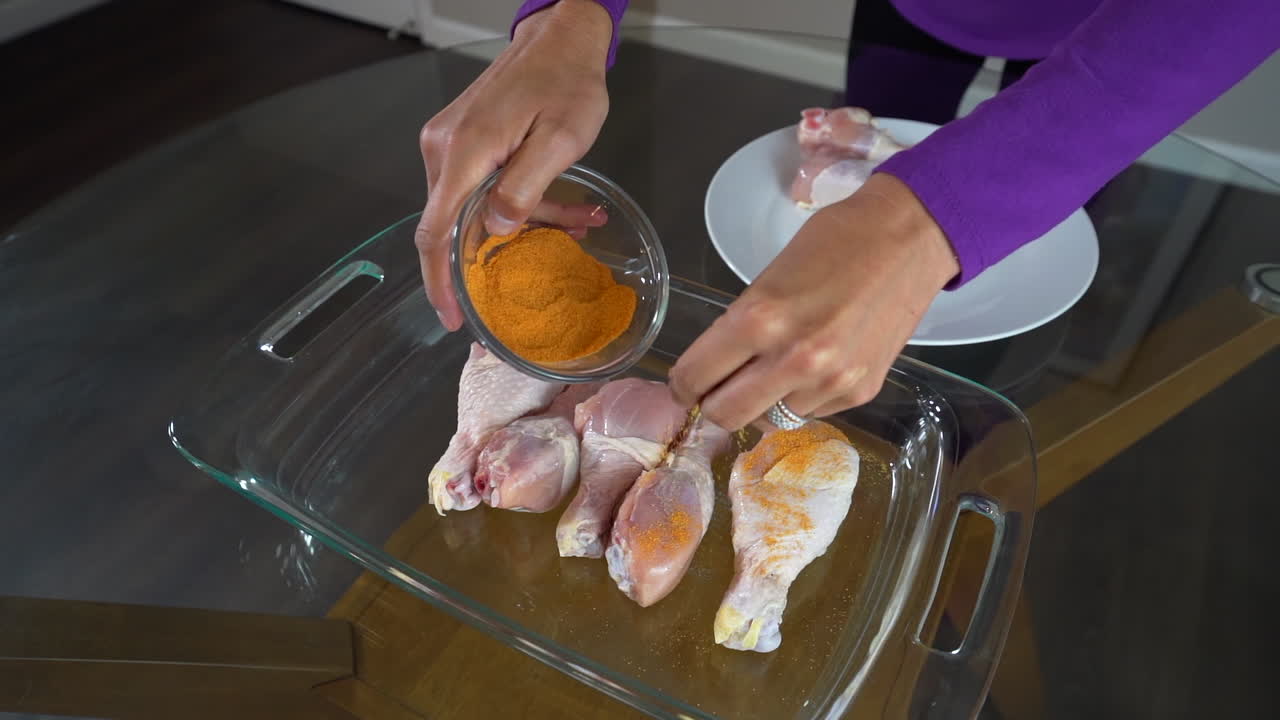 espolvorear condimento de naranja sobre muslos de pollo crudo