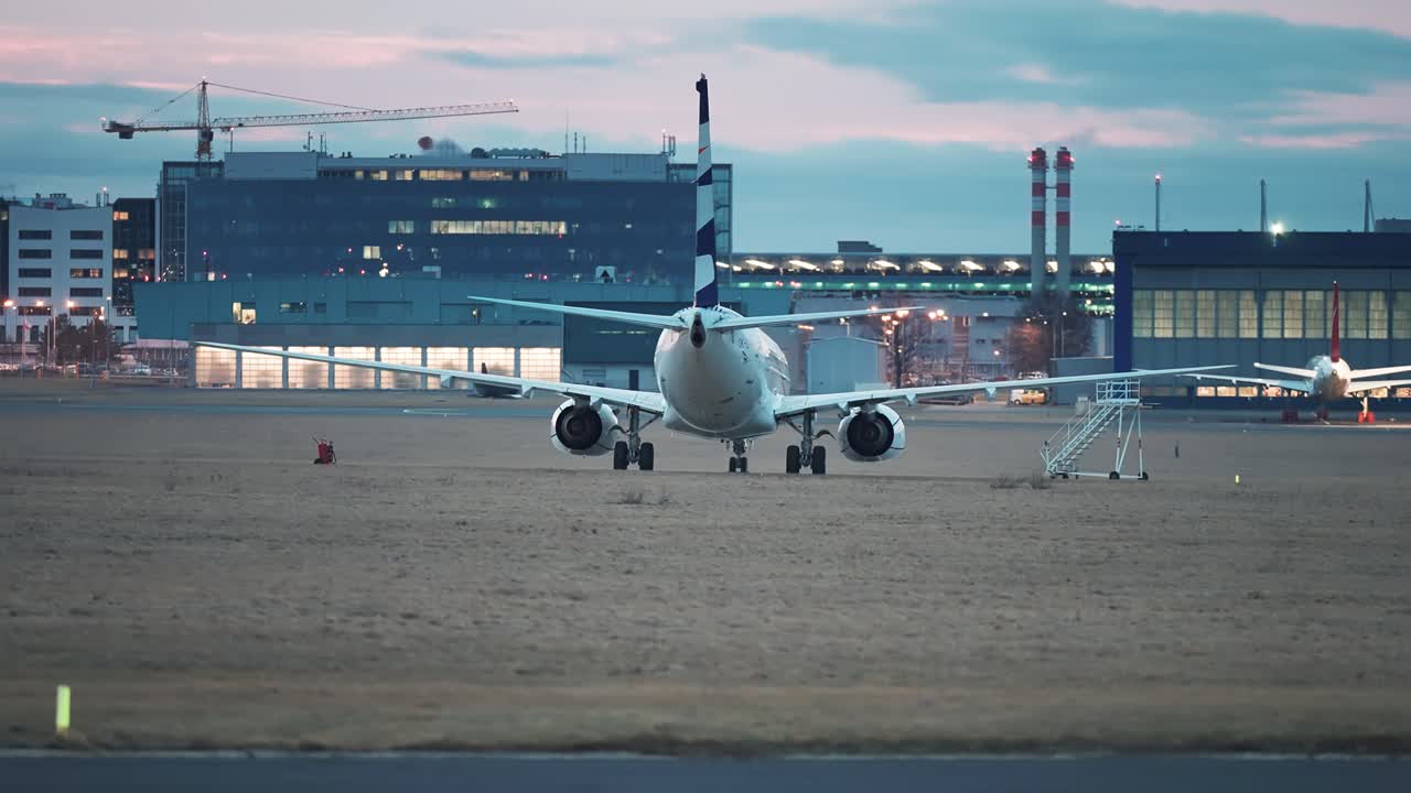 un avión de pasajeros está estacionado en el campo de aterrizaje de vaclav havel aeropuerto en praga, con la torre de control de vuelo, edificios administrativos y hoteles en el fondo