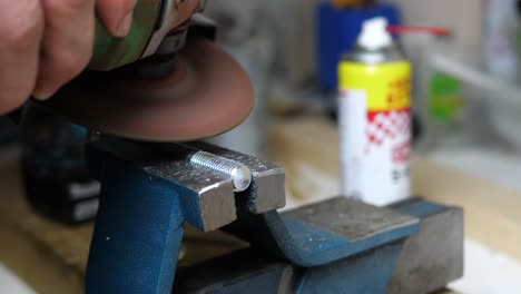 professional craftsman use angle grinder on steel bolt inside of work shop