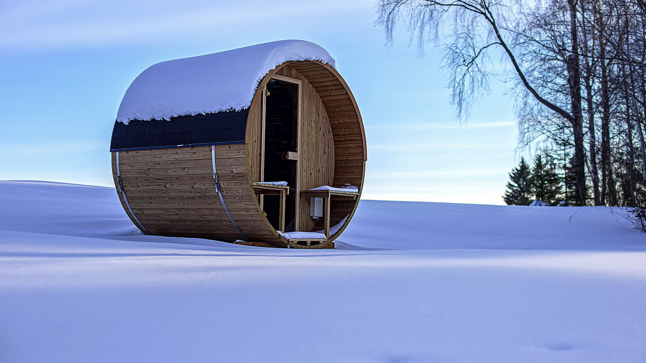 Una casetta in legno portatile e indipendente in mezzo a un terreno innevato e sgombro e un time-lapse del tramonto.