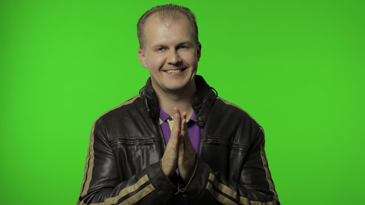 hombre rocker en chaqueta de vaqueros marrón frotando las manos y planeando una idea astuta. planeando una broma