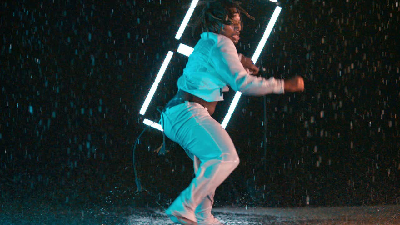 Young black African-American performing Capoeira dance in wet indoor lighting