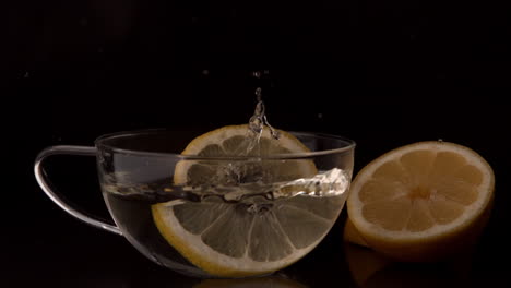 lemon slices falling into glass cup of water