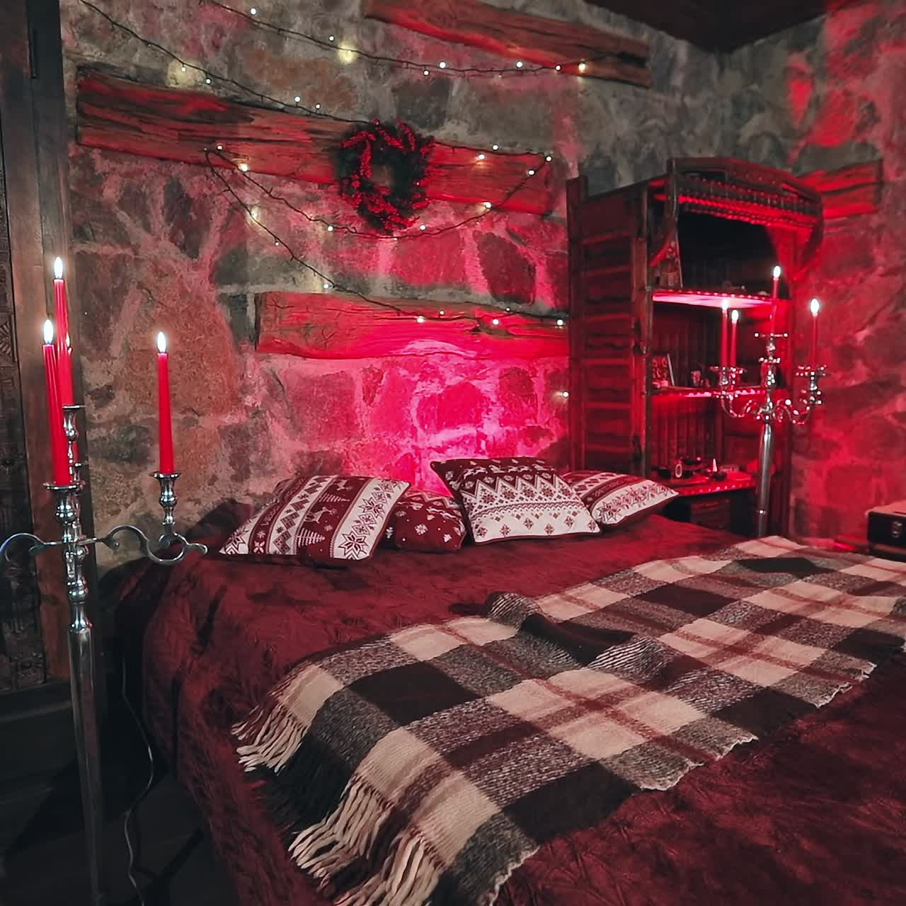 Cozy room with Christmas decorations. Christmas decorated bedroom with many lights, candles and red light. Room with garlands