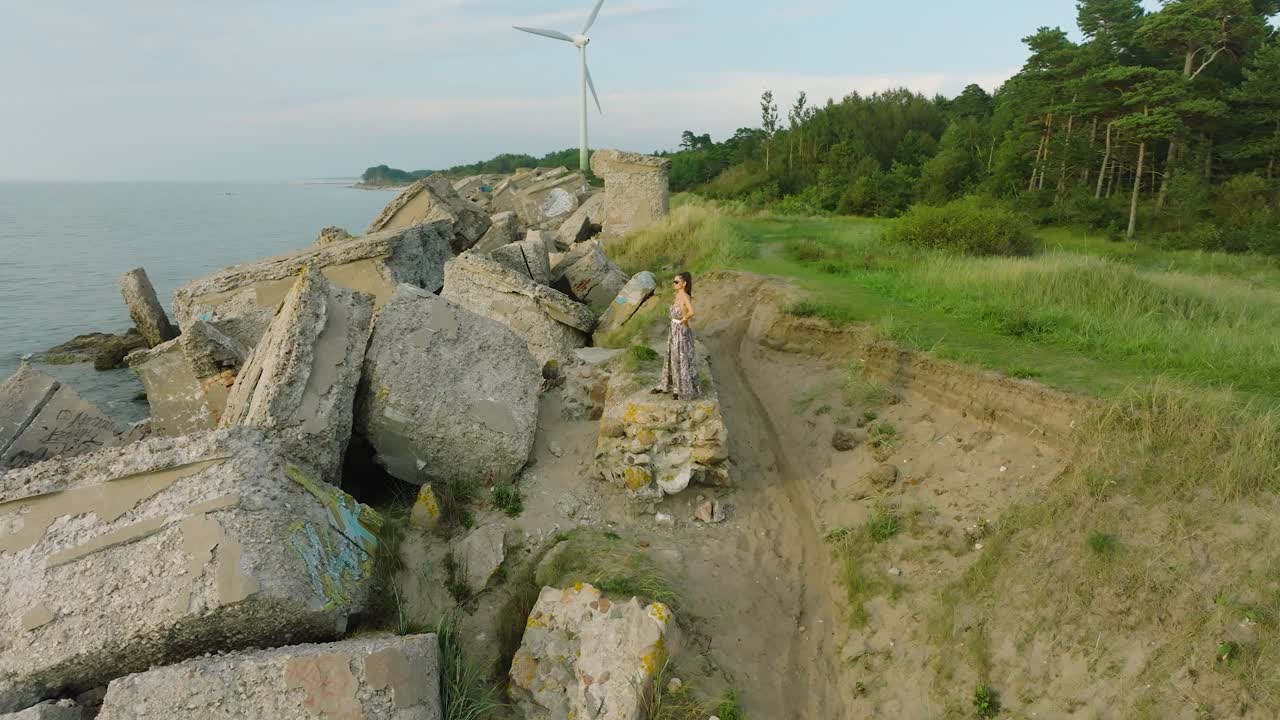 vista aérea de una hermosa joven caucásica romántica en un vestido largo en la playa de arena blanca con antiguas ruinas, noche soleada de verano, puesta de sol, hora dorada, amplia órbita de avión no tripulado