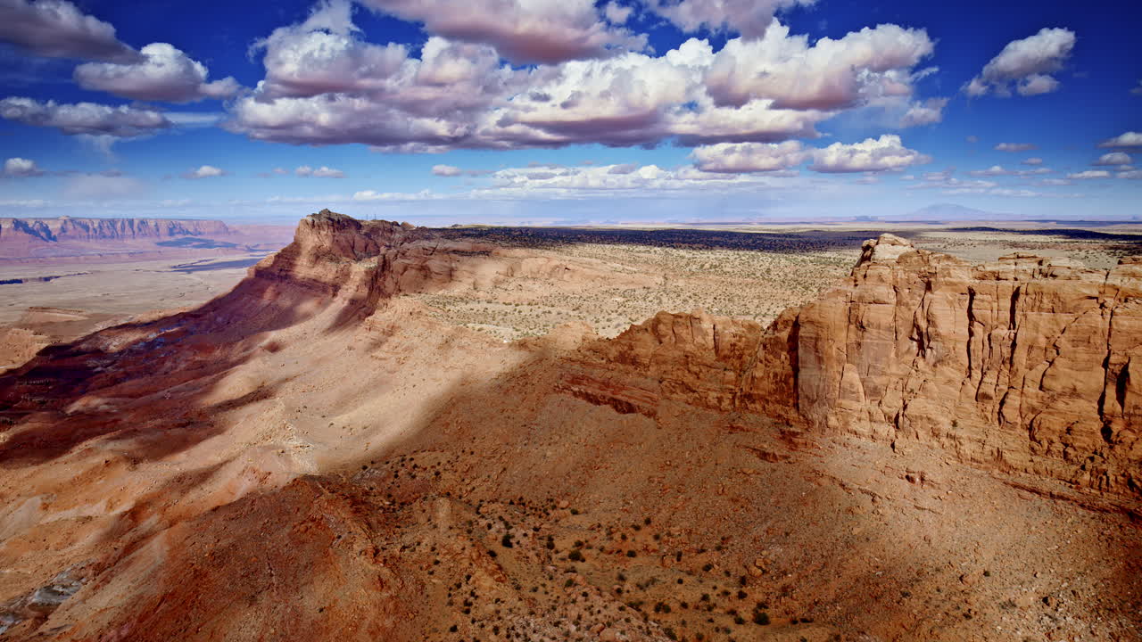 Drone shot panning to show dramatic landscape with canyons, mesas and red rock formations