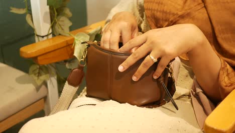 woman taking something out of a brown purse