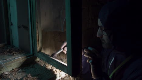 vista detallada del investigador de ciencias forenses, cepillado del marco de la ventana vieja, búsqueda de evidencia de la escena del crimen
