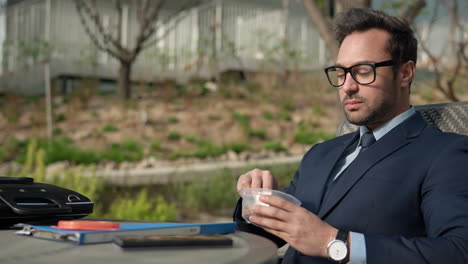 hombre de negocios relajado comiendo nueces de pecan nutritivas sentado en un parque