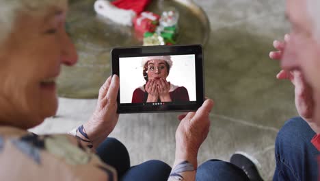 Senior-caucasian-couple-using-tablet-for-christmas-video-call-with-happy-woman-on-screen