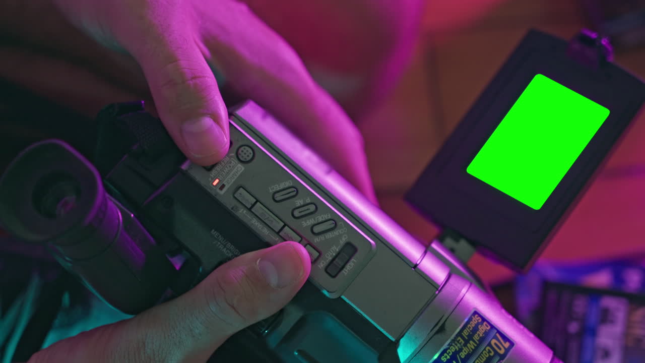 Handen bedienen vintage camcorder met groen scherm monitor.