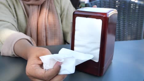 mujer tomando una servilleta de un poseedor en un restaurante