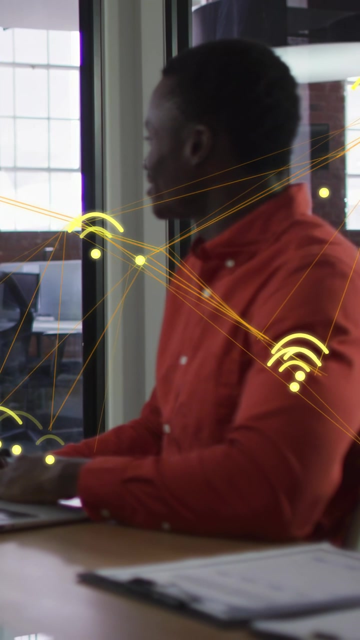Vertikal video: Mand taster på bærbar computer i forbindelse med arbejde, kollega kommer ind og får ham til at kigge op, gule grafikker bevæger sig