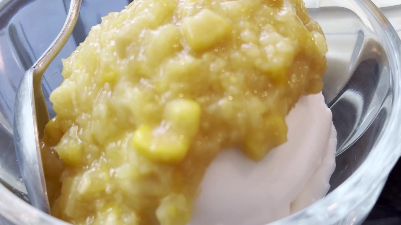 Nærbilde av thai kokosnøttis toppet med søt mais, servert som en forfriskende tropisk dessert med kremet tekstur og elegant presentasjon