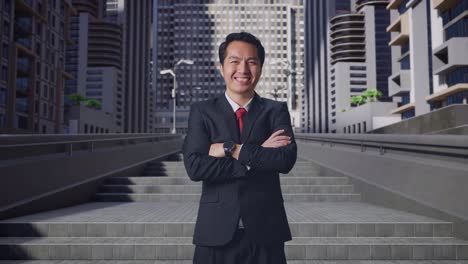 an asian business man crossed arms and warmly smiling in city