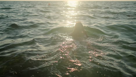 mujer nadando en el océano al atardecer