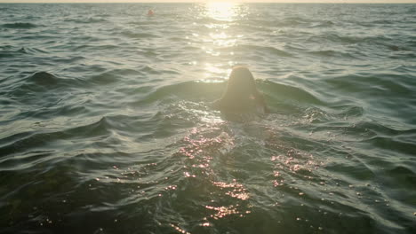 woman swimming in the ocean at sunset