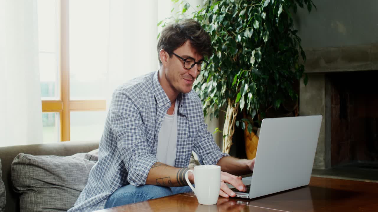 hombre trabajando desde casa en una computadora portátil, bebiendo café