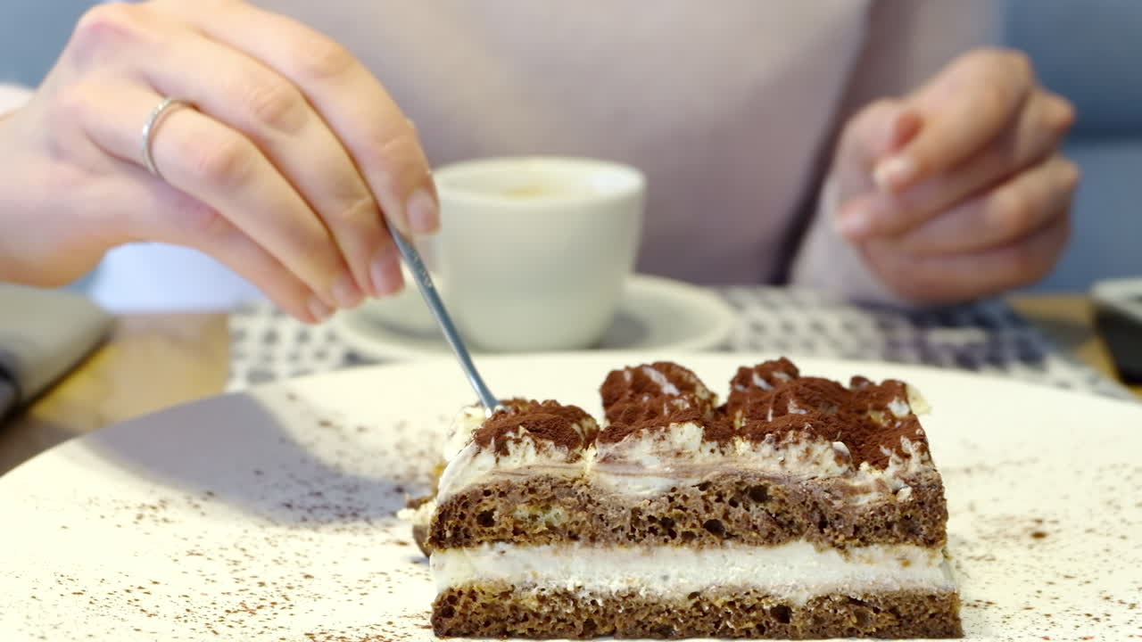 Close up of a woman eating tiramisu at a cafe