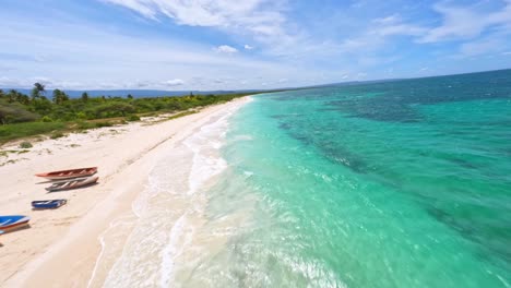 FPV-drone-flight-over-exotic-and-remote-Caribbean-beach,-fishing-boats-on-sand