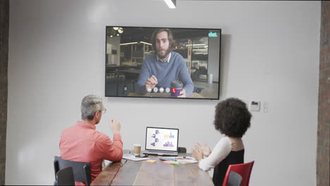 Diverse-business-people-on-video-call-with-caucasian-male-colleague-on-screen