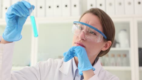 a female scientist examines a test tube in a laboratory