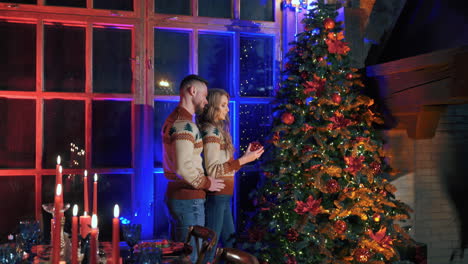 beautiful cheerful young couple in love decorating christmas tree indoors. new year holidays spirit video.
