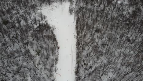 skiers and snowboarders skiing on snow slopes with ski lift at weekend. drone flying over snowy slope with skiers and snowboarders at ski resort on a frosty winter day: drone view