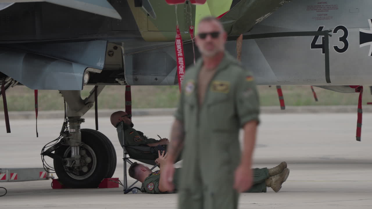 Militari a riposo sotto un jet da combattimento sul piazzale