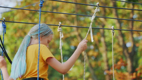 a child climbs ropes high in the trees - having fun in a rope city in an amusement park